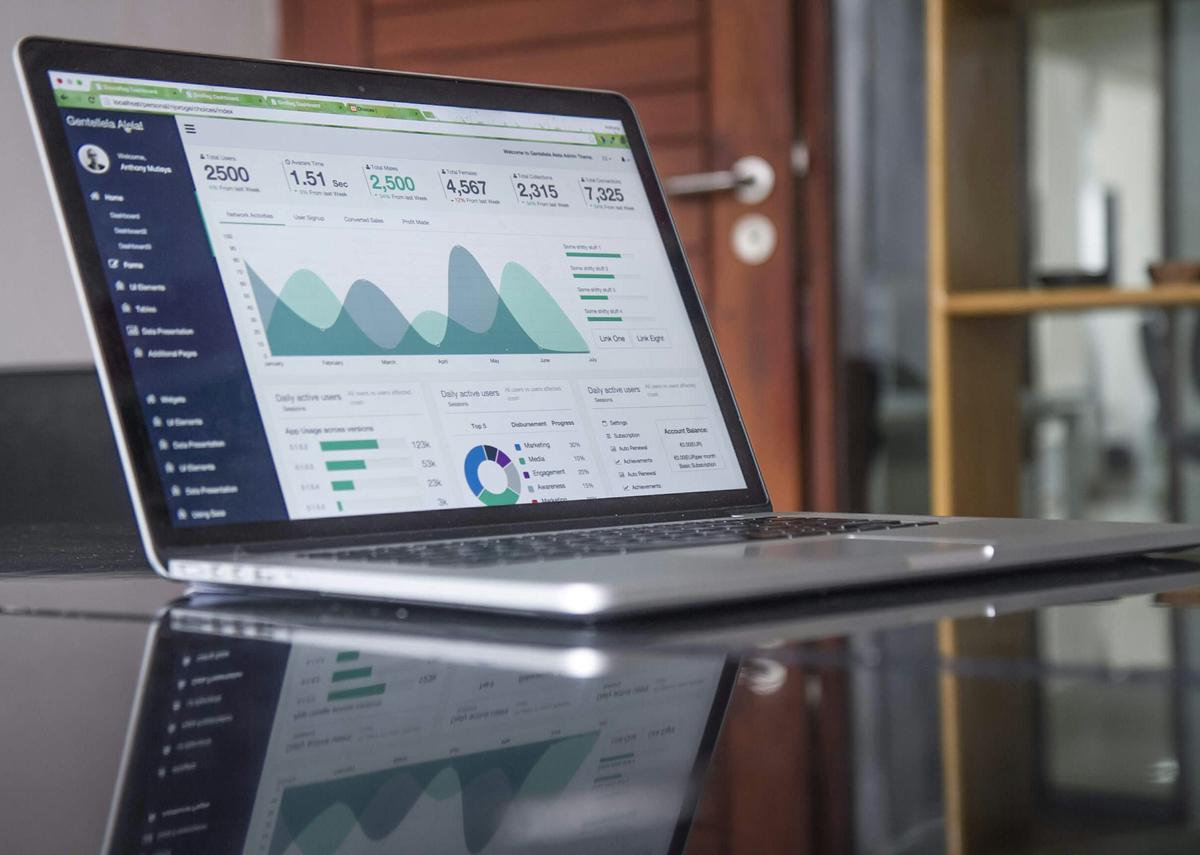 A laptop displaying the Ezoic platform dashboard with various charts and graphs representing ad performance and site metrics.