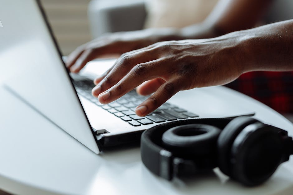 A person typing on a keyboard with headphones on, symbolizing transcription skills and tools.